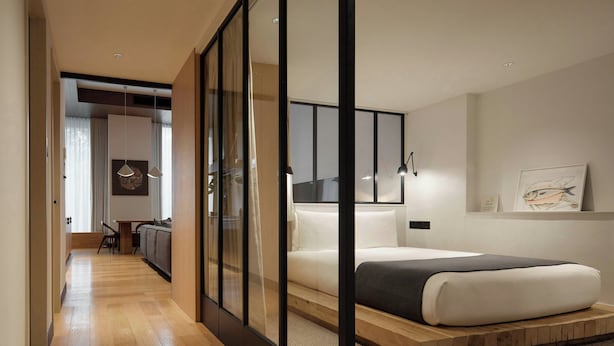 Un dormitorio moderno con una cama, una plataforma de madera, un escritorio y una silla.