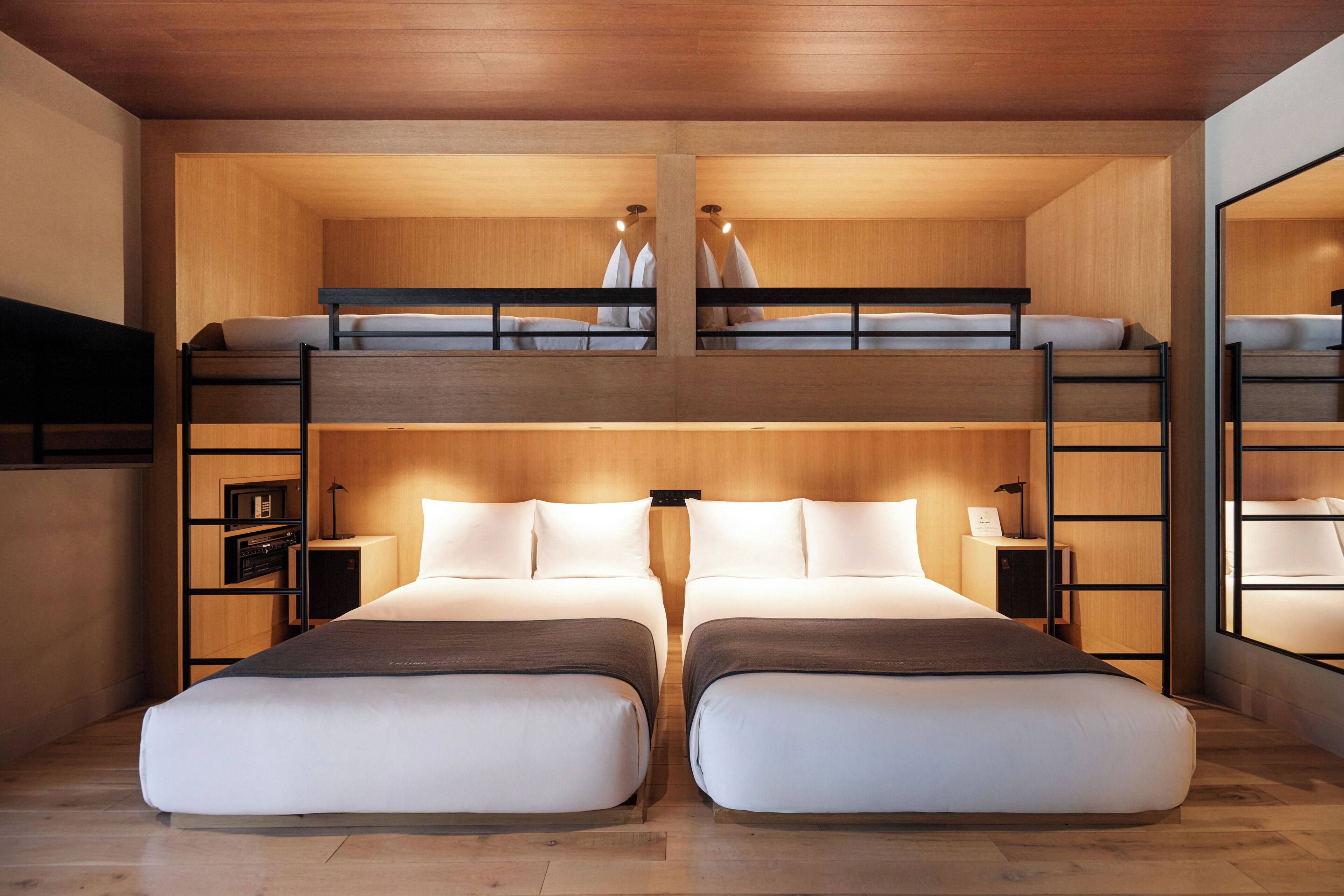 A room with two beds, a wooden ceiling, and a built-in TV.