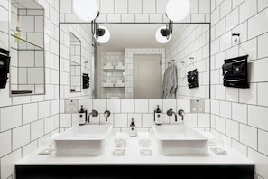 A modern bathroom with two sinks, a large mirror, and a tiled wall.