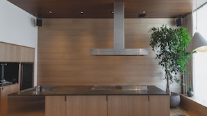 A modern kitchen with a central island, wooden cabinetry, and a large stainless steel range hood.
