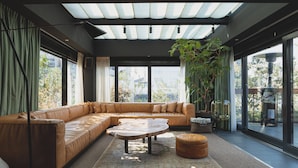 Una sala de estar moderna con un sofá seccional de cuero, una mesa de centro redonda y una planta grande en maceta.