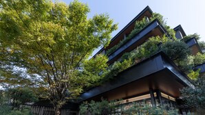 Un edificio moderno con varios balcones, rodeado de abundante vegetación y árboles.