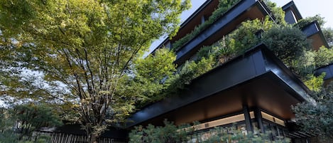 Un edificio moderno con varios balcones, rodeado de abundante vegetación y árboles.
