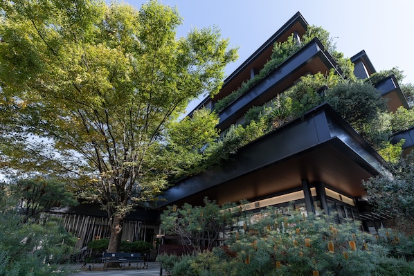 A modern building with multiple balconies, surrounded by lush greenery and trees. - TRUNK (HOTEL) CAT STREET (Tokyo)