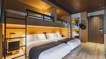 Habitación de hotel moderna con literas, una mesita de noche, un espejo y un armario.