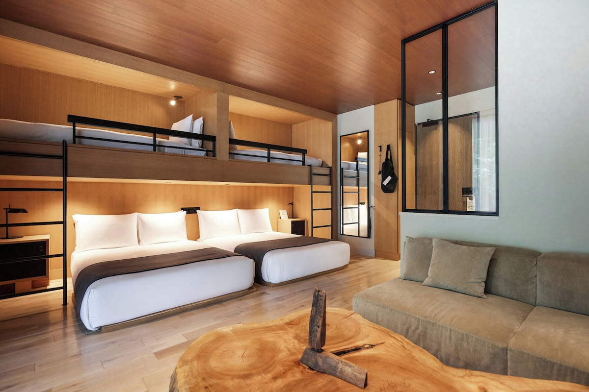 A modern interior with bunk beds, a sofa, a wooden coffee table, and a large mirror.