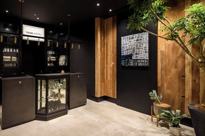 A modern hotel lobby with a black and wood interior, a glass display case, and a large abstract art piece on the wall.