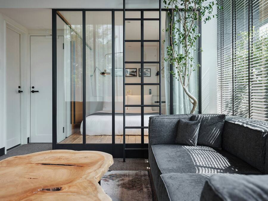 Ein modernes Interieur mit einer Couch, einem Holztisch und einer Schiebeglastür, die zum Schlafzimmer führt.