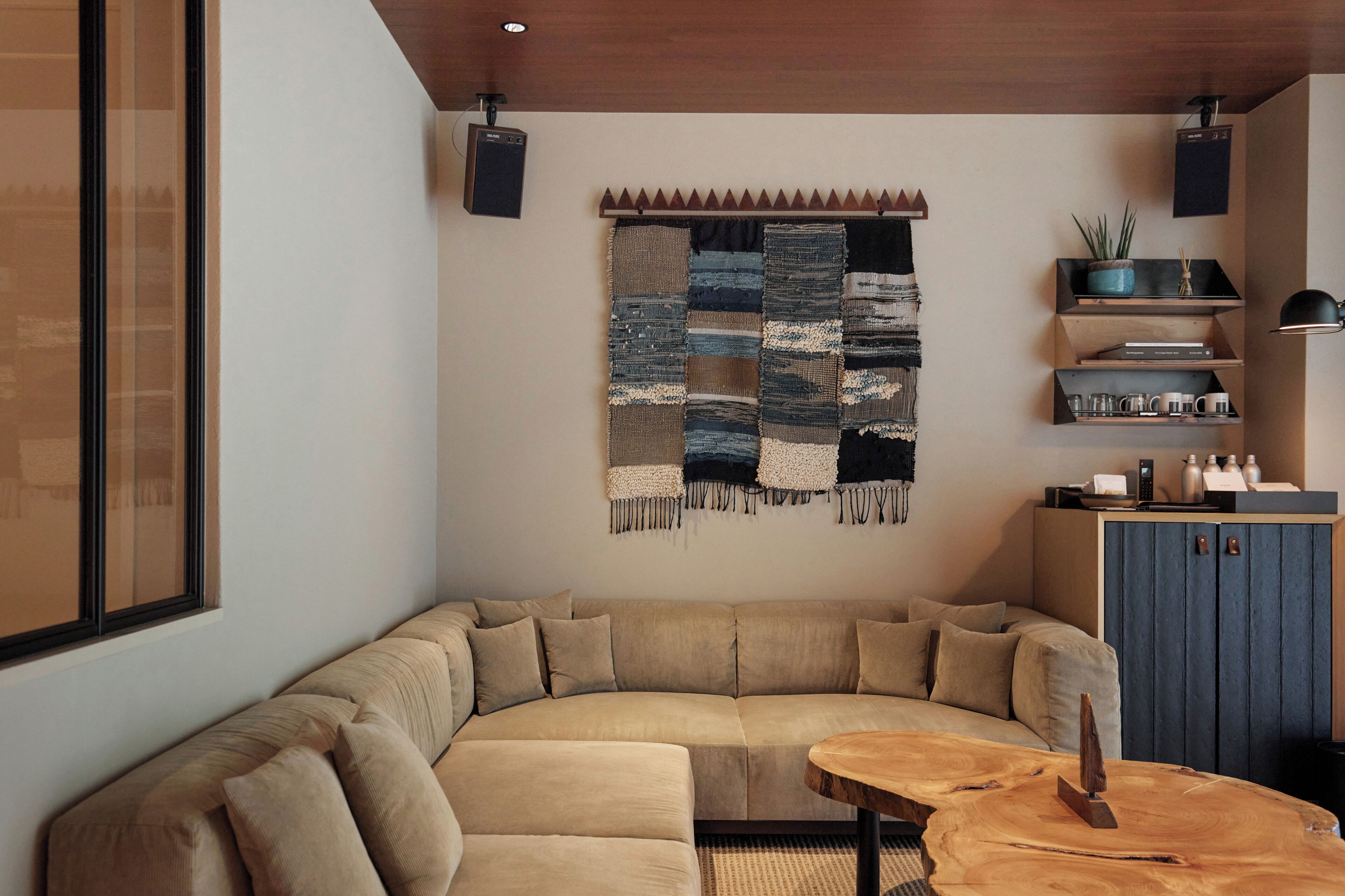 Una sala moderna con un amplio sofá seccional en forma de L, una mesa de centro de madera y un estante de pared con objetos decorativos.