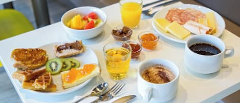 Una mesa de desayuno con platos de comida, un vaso de jugo de naranja y una taza de café.