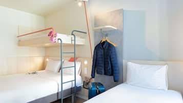 A hotel room with bunk beds, a ladder, a hanging coat rack, and a suitcase.
