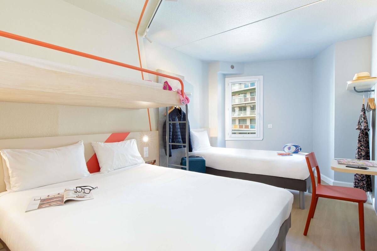 Een hotelkamer met stapelbedden, een bureau, een stoel en een raam.