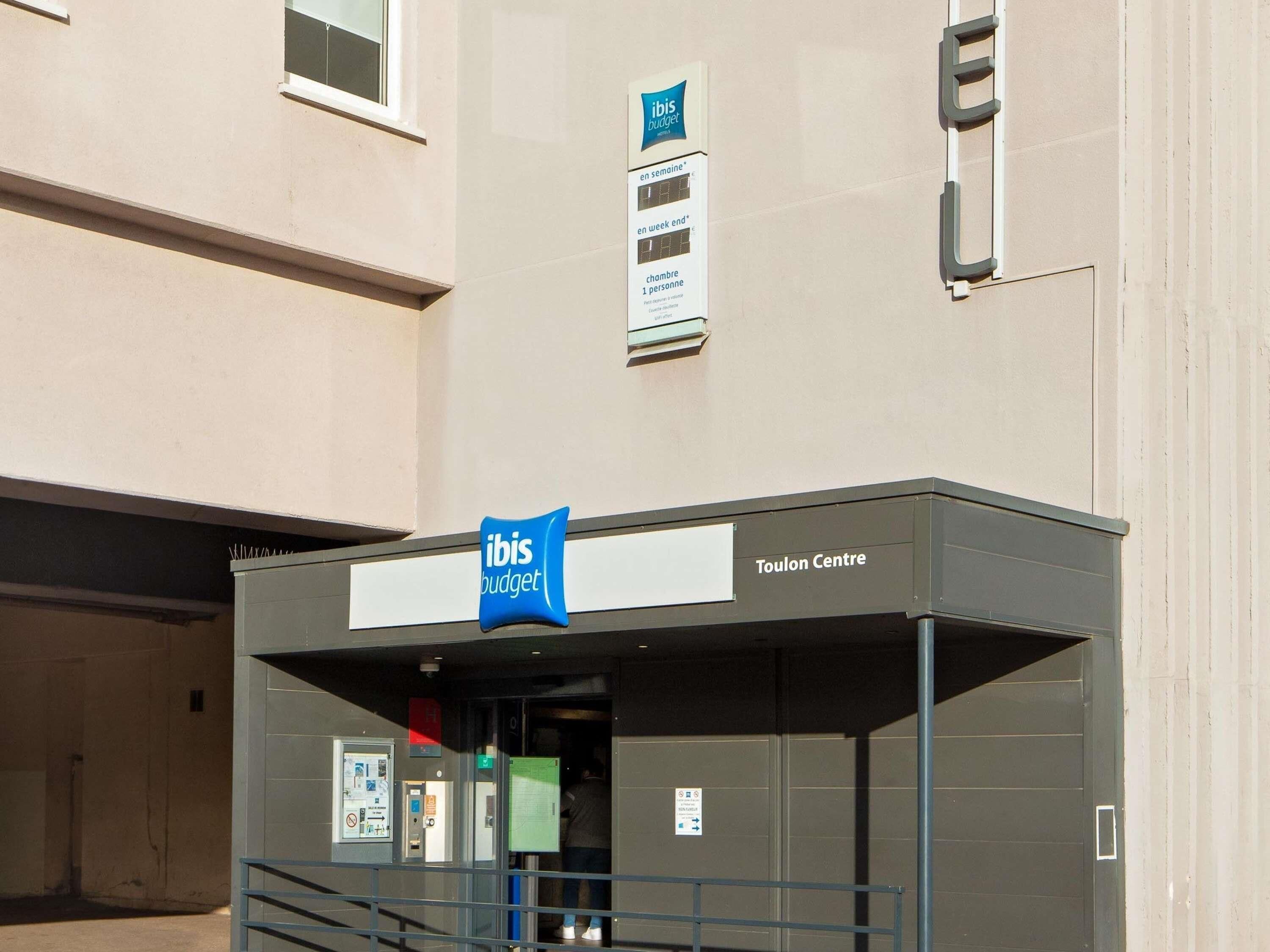A building with a sign for 'Toulon Centre' and 'ibis budget' indicating a budget hotel.