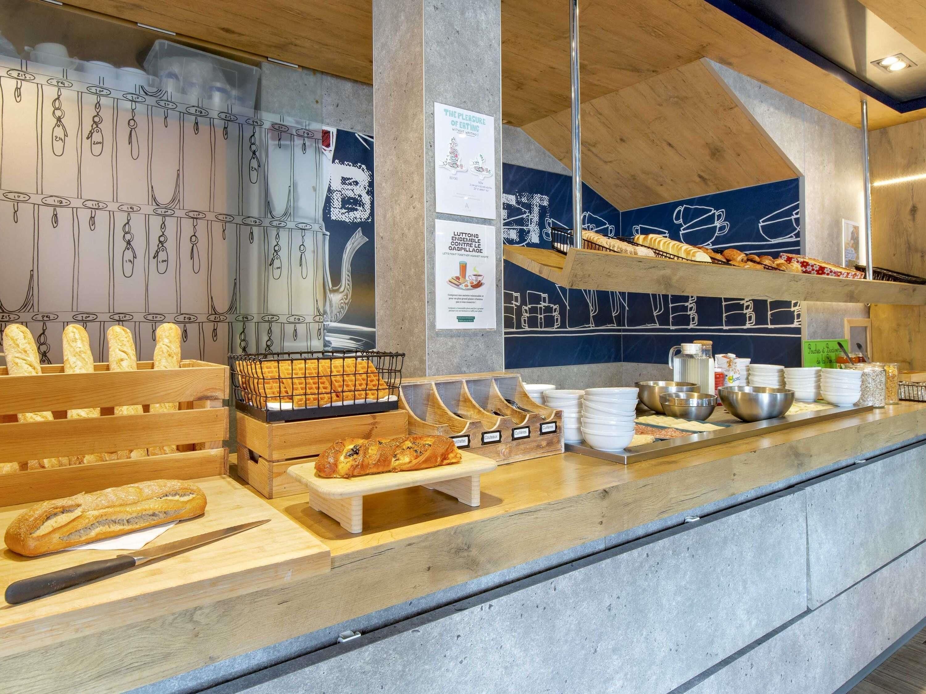 Un comptoir de boulangerie où l’on trouve du pain, des gaufres et des pâtisseries, ainsi que divers ustensiles et récipients de cuisine.