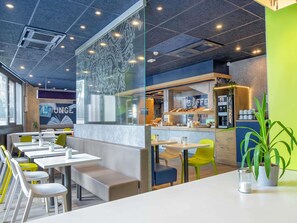 Un café moderne doté d’une paroi en verre, d’un espace salon et d’un comptoir de cuisine visible.