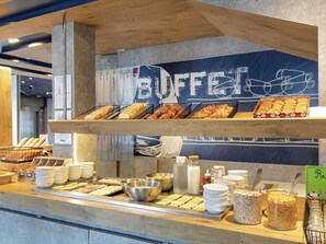 Un buffet proposant une variété d’aliments, notamment du pain, des pâtisseries et des céréales.