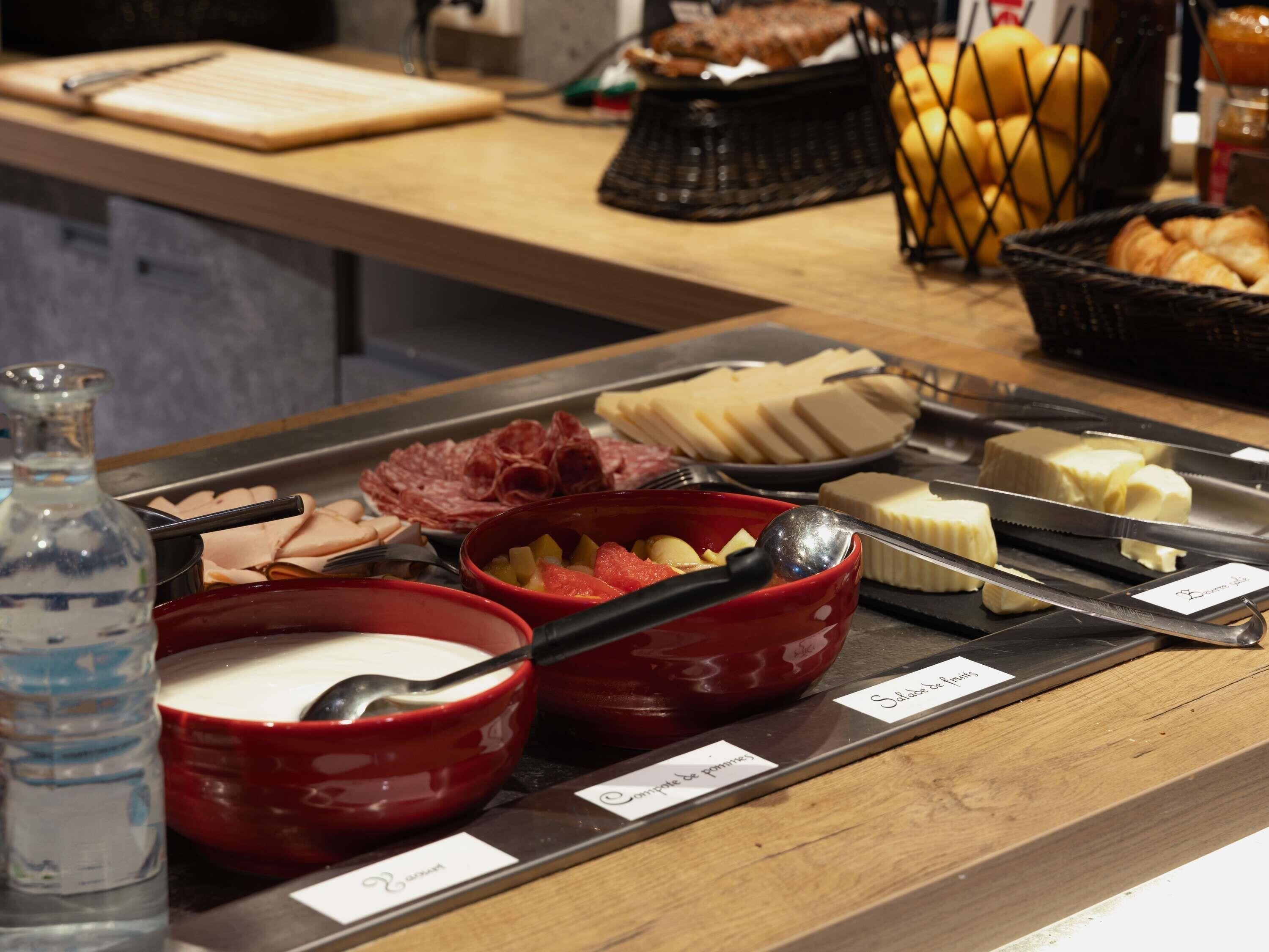 Een buffet met diverse gerechten, zoals vleeswaren, kazen en fruit.