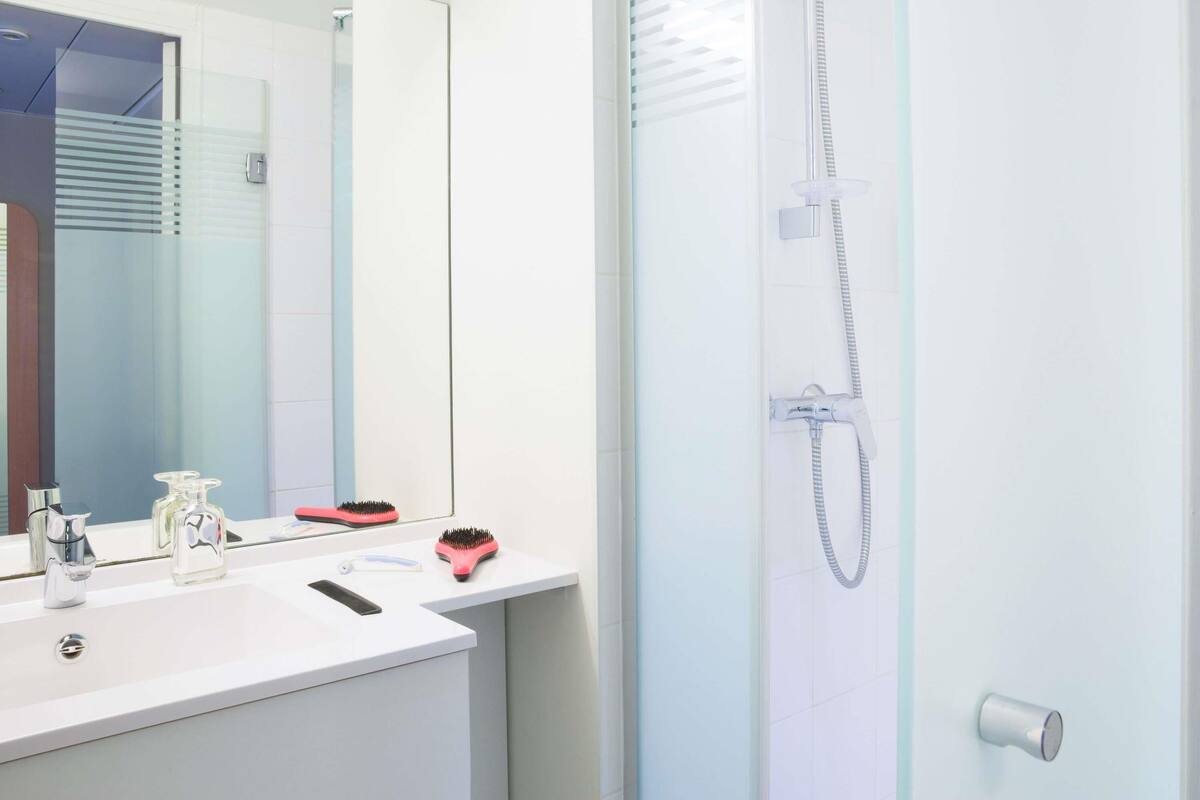 A bathroom with a white sink, mirror, and shower.