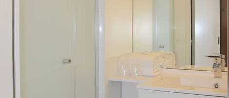 A bathroom with a glass shower door, a white sink, a mirror, and a towel on the counter.