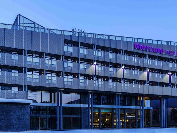 A modern hotel with a metal facade, multiple balconies, and a prominent 'Mercure Hotel' sign.