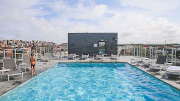 Een seizoensgebonden buitenzwembad en ligstoelen