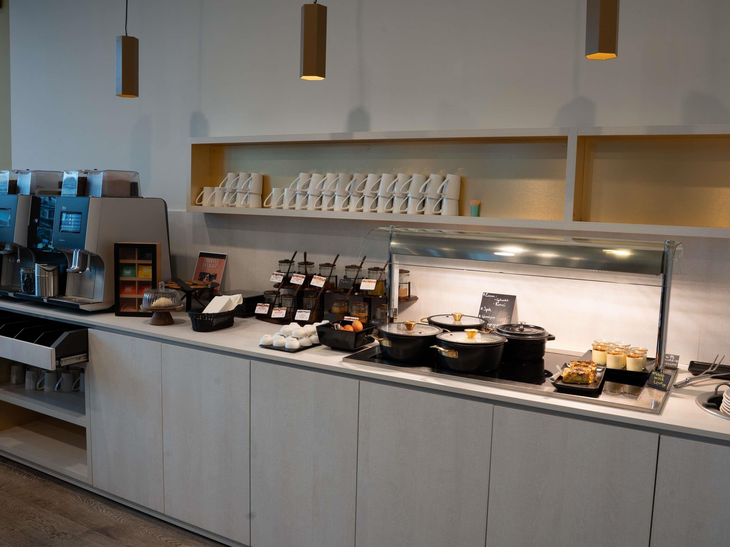 Un comptoir de buffet avec des machines à café, une variété de plats et un assortiment de tasses.