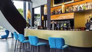 A bar area with blue bar stools, a counter with a variety of bottles, and a TV mounted on the wall.