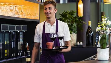 A bar area with a bartender holding a tray with glasses and bottles.