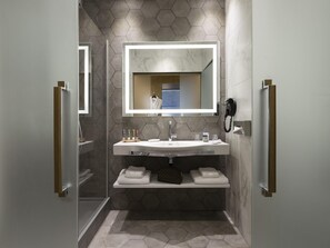 Un baño moderno con un espejo grande, un lavamanos, un perchero para toallas y una ducha.