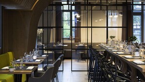 Un restaurante moderno con una larga mesa de comedor, sillas y vistas a través de amplios ventanales.