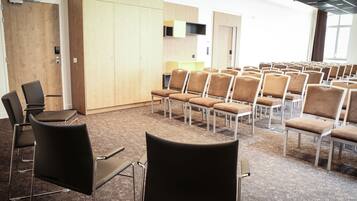 A conference room with rows of chairs, a wooden wardrobe, and a small table.
