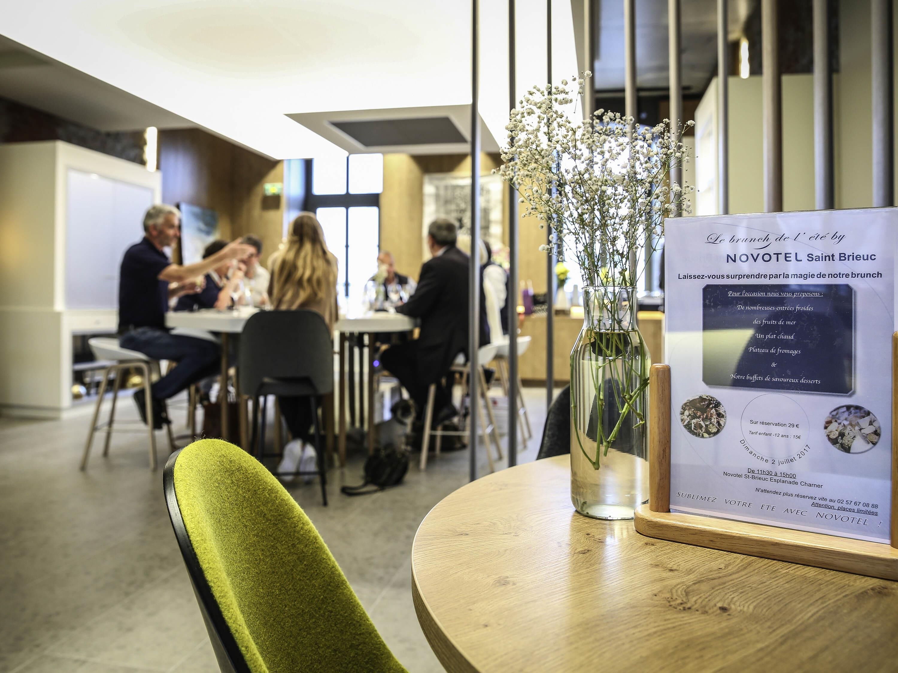 A hotel dining area with a table displaying a menu and a vase with flowers.