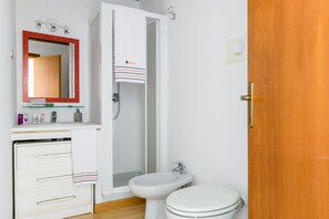 A bathroom with a white sink, a bidet, a toilet, and a mirror with a red frame. - JOIVY Old Town Milano (Milan)
