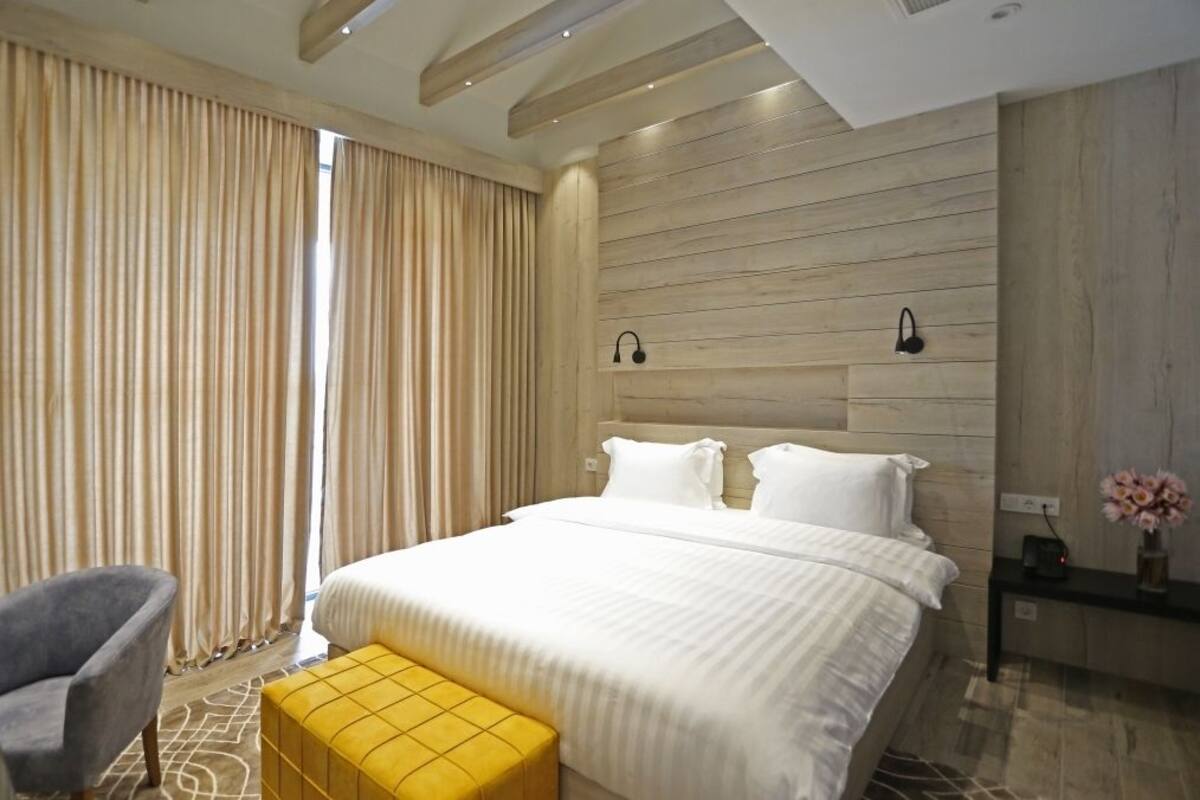 Habitació d'hotel moderna amb un llit gran, una cadira i una taula petita amb un ram.