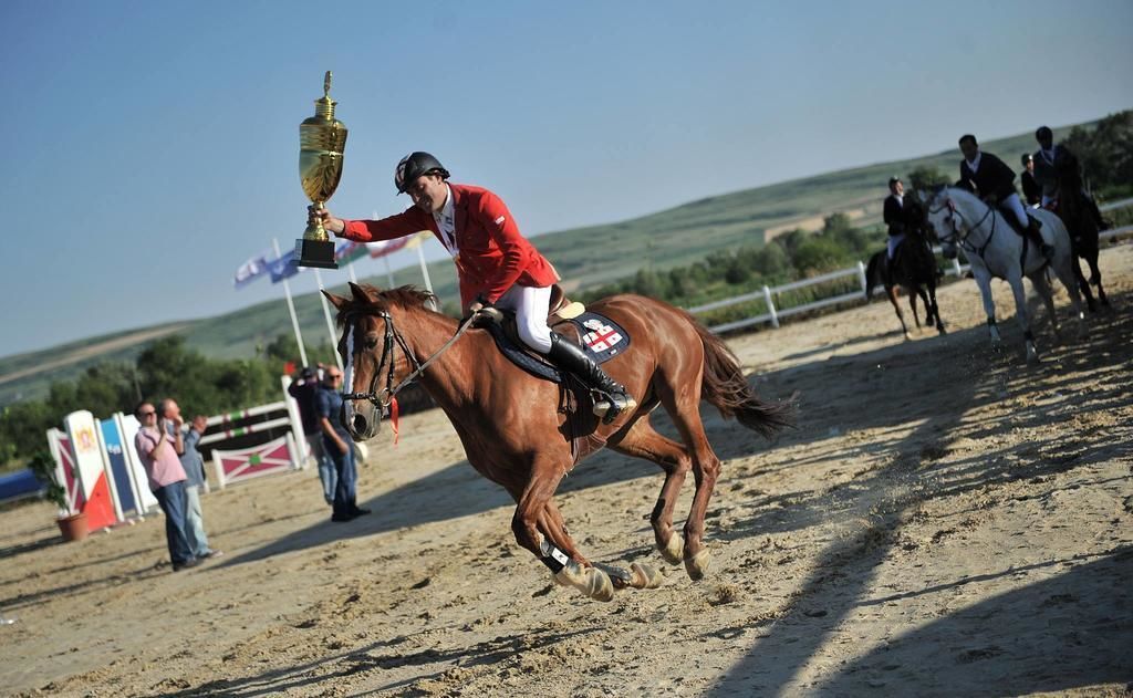 Un jinete a caballo al galope, sosteniendo un trofeo.