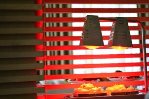 Exposição de comida com fundo vermelho e duas luzes direcionadas por cima.