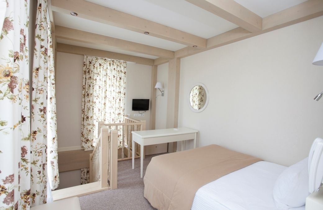 A bedroom with a bed, a desk, a chair, and a television.