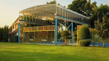 Un edificio moderno con fachada de vidrio, elementos estructurales azules y un área exterior cubierta.