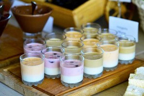 Une sélection de desserts en couches, présentés dans de petits verres, sur une planche en bois.