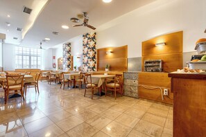 A restaurant with wooden tables and chairs, a kitchen area, and a patterned wall. - Hotel Vilagarcia (Vilagarcia de Arousa)