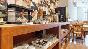Una barra de desayuno con cafetera, cereales y frascos de condimentos.