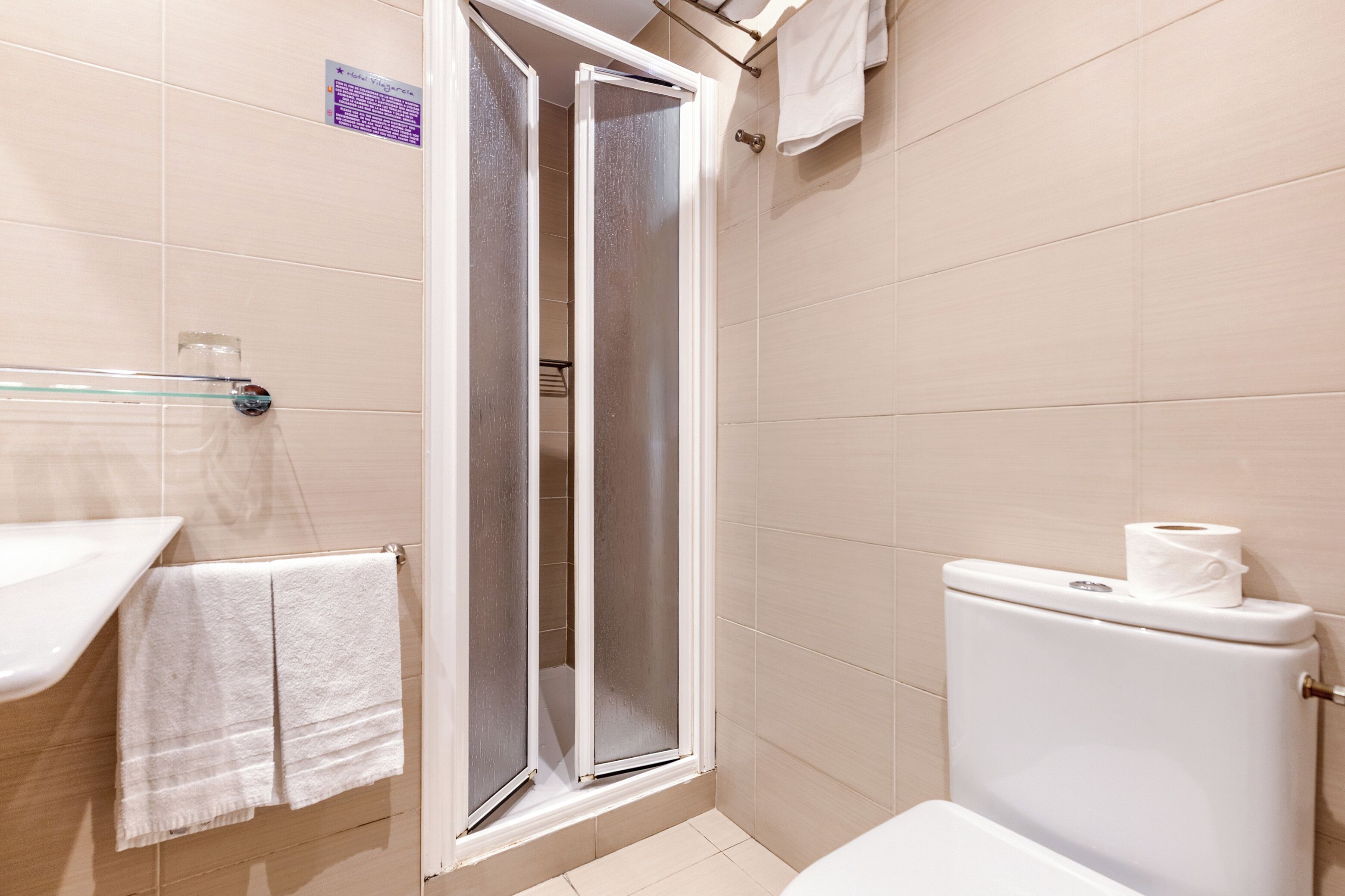 Une salle de bain avec douche, toilettes et lavabo.