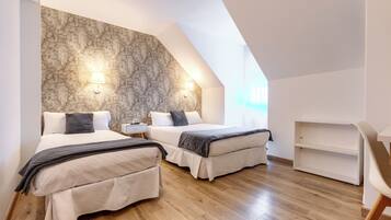 A modern bedroom with two beds, a stone accent wall, and a skylight.