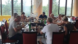 A group of people dining at a table in a modern restaurant with large windows and a chandelier. - Hotel Park Green (Poti)