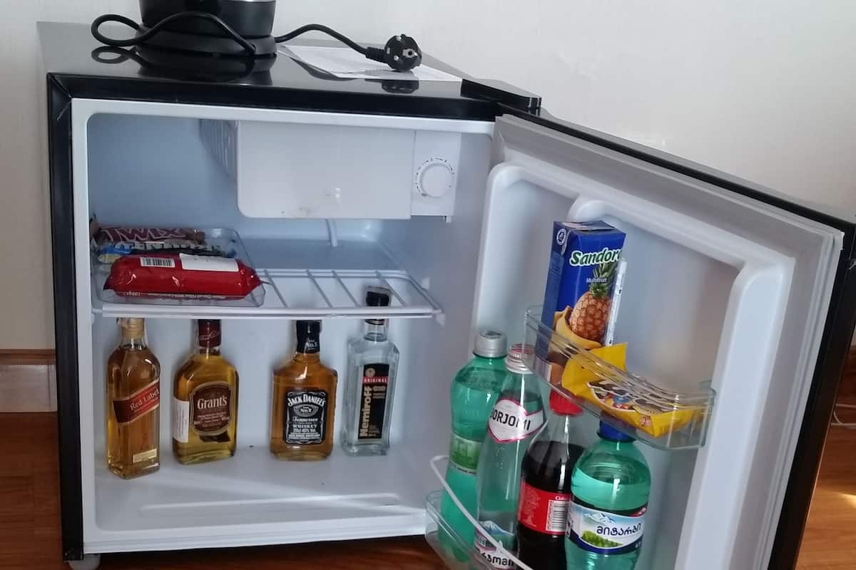 Un refrigerador abierto con diferentes bebidas y aperitivos.