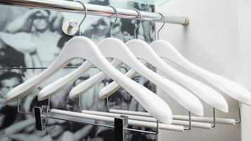A clothing rack with white hangers against a wall with a black and white patterned background.
