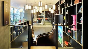 A modern interior with a staircase, glass display cases, and shelves with various items.