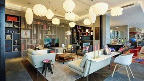 A modern living room with a sofa, coffee table, and TV. There are bookshelves and decorative items. - citizenM Taipei North Gate (Taipei)