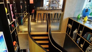 A spiral staircase in a modern interior space with bookshelves and seating areas. - citizenM Taipei North Gate (Taipei)