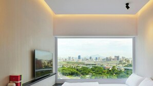 A modern hotel room with a large window offering a city view, a flat-screen TV mounted on the wall, and a neatly made bed. - citizenM Taipei North Gate (Taipei)